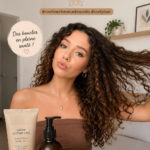 Femme avec des cheveux bouclés bien définis et brillants, reflétant une routine capillaire saine.